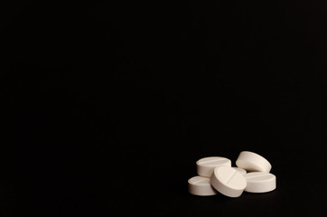 Close-up. A handful of tablets on the right on a black background