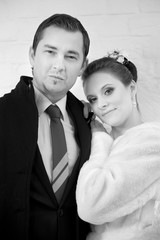 Wedding portrait of the bride and groom on the background of a white brick wall on the street. Close-up. Black and white image.