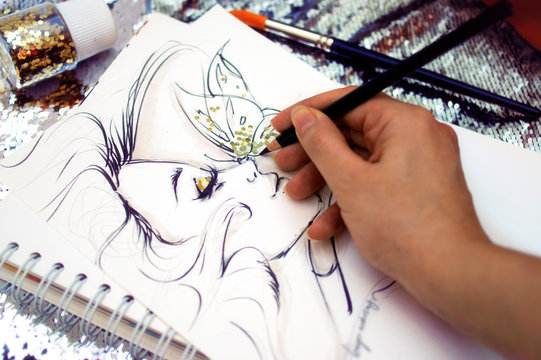 Fashion illustrator drawing a sketch with glitter