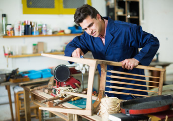 Man carpenter in furniture repair workshop