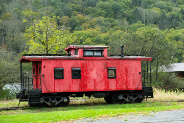 Fototapeta na wymiar Old red caboose sitting idle on the tracks