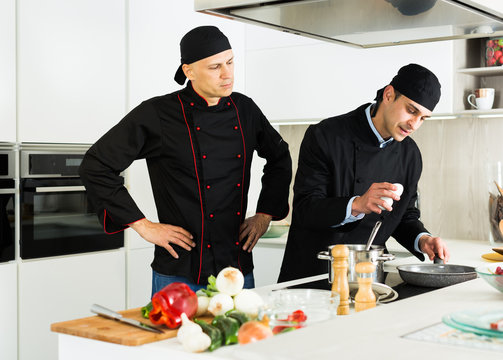 Male chefs  in black uniform having quarrel at workplace on kitchen