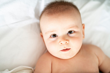 happy cute baby lying on white sheet