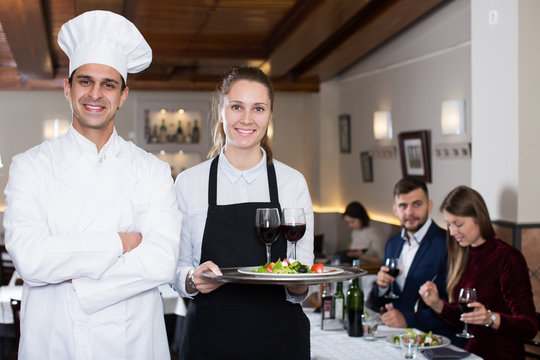 Portrait of confident male chef and smiling waitress