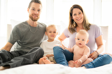 Family of four with baby having fun on bed