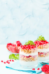 Pomegranate parfait - sweet organic layered dessert with granola flakes, yogurt and ripe fruit seeds.