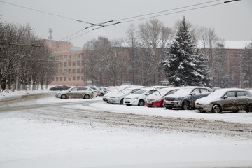 Snow-covered cars on the roadway. Snowfall.