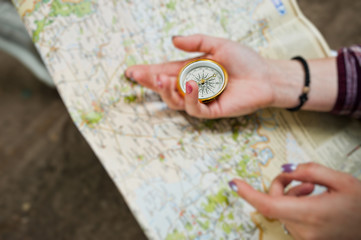 Close-up photo of female hands with compass on a map.