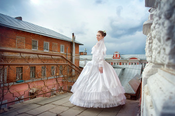 Portrait of a bride in a wedding dress and with a long veil on the background of the ancient city and a cloud in the autumn day.