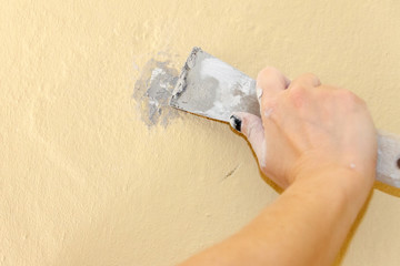 Hand of a young woman covering holes with putty