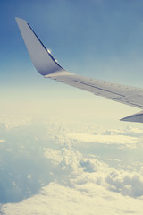 Obraz premium Wing of an airplane flying in the sky above the clouds, view from the porthole