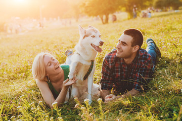Fototapeta premium Dog with owners spend a day at the park. Young couple and husky running, playing and having fun.
