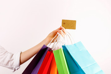 Cropped shot of female hand holding bunch of different colorful blank shopping bags with golden...