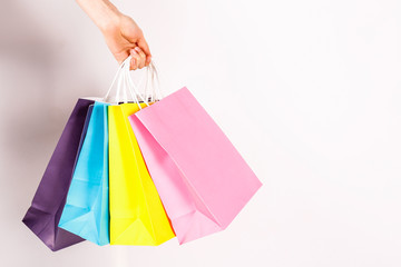 Cropped shot of female hand holding bunch of different colorful blank shopping bags over isolated...