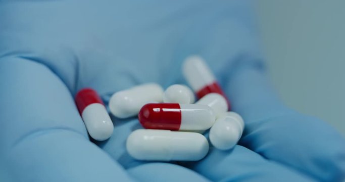 Close up of a scientist hand holding and showing some white pills in a laboratory. Concept: Scient, chemistry, future. Shot on RED 8K
