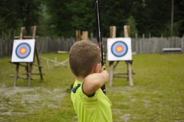 Boy aims at target with bow and arrow