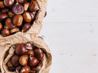 Castagne di bosco: i frutti dell'autunno su tavolo bianco con spazio vuoto
