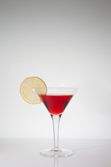 Cocktailglas mit rotem Inhalt und Zitrone