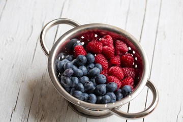 Fresh picked Blueberries and raspberries in a metal sieve