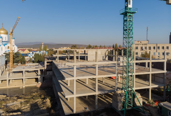 Fototapeta premium High rise building under construction. The site with cranes against blue sky.