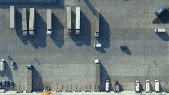 Aerial top view of a row of semi trucks standing on the logistic terminal parking