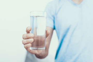 Close up. Man in T-shirt Holding Glass of Water.