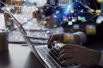 Business man works in office with laptop in the foreground. Concept of teamwork and partnership. double exposure with network effects
