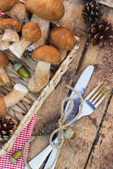 Raw white mushrooms, pine cones with dry decorations on the wooden table