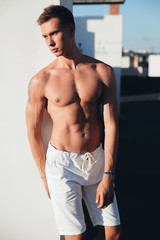 Fototapeta premium Male model, sporty man, juicy guy on the roof, man in a white shorts