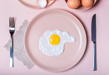 Scrambled eggs on a beige plate. Nearby lie on the table fork and knife. simple breakfast