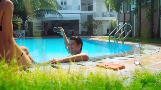 guy pictures slim girl in bikini sitting on pool barrier