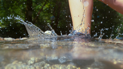 HALF UNDERWATER: Trekker wearing waterproof boots stepping into mountain stream.