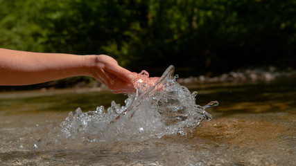CLOSE UP: Unrecognizable woman scoops up a handful of refreshing river water