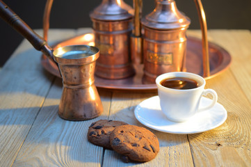 a biscuits and a Cup of coffee near the sugar bowl and container with coffee on rustic wooden table