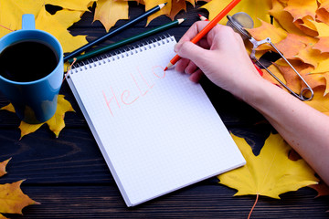 Fall paint on a black table. Notepad with colored pencils. Tasty tea in a blue cup. Yellow leaves...