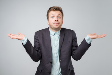 Young caucasian man in suit and white shirt is confused