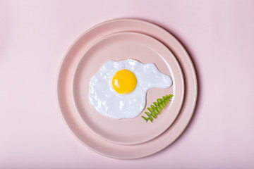 fried eggs on beige plate with a small leaf . Laconic. view from above