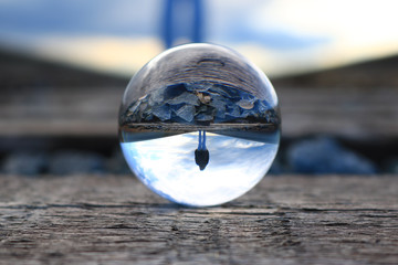Refection of a woman walking on the train tracks in a lens ball