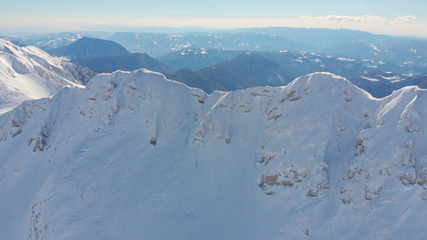 Fototapeta na wymiar AERIAL: Breathtaking view from the air of a mountain range covered in fresh snow