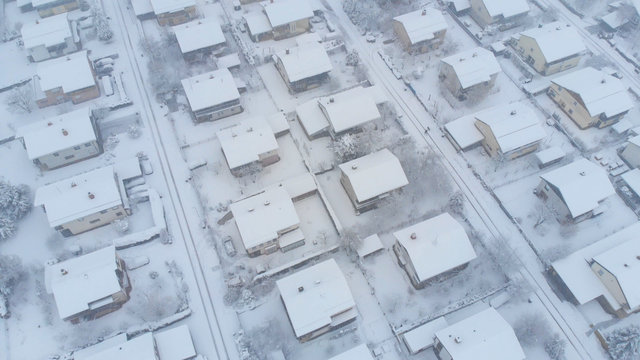 AERIAL: Flying Above The Snowy Rooftops And Streets Of Suburban Neighborhood.