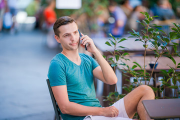 Caucasian boy is holding cellphone outdoors on the street. Man using mobile smartphone.