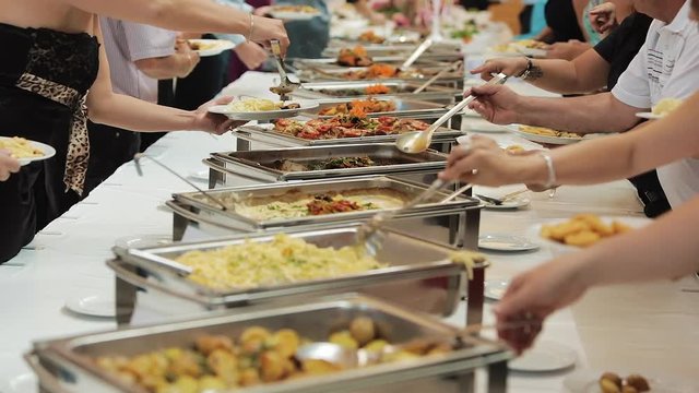 People group catering buffet food indoor in luxury restaurant with meat colorful fruits and vegetables. Close up. Banquet, lunch, bad nutrition, gluttony concept