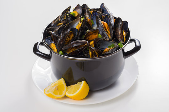 Black pan with cooked with green onion, parsley marinated high quality mussels, mussels from Brussel