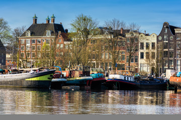 AMSTERDAM, NETHERLANDS - APRIL 10, 2018: Amsterdam cityscape with typical dutch houses and boats from the Oosterdok in the Netherlands.