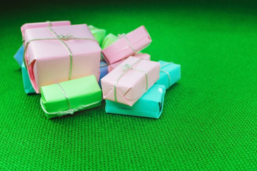 Cute green gift with red christmas balls on green abstract light background