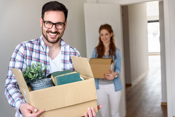 Fototapeta na wymiar Beautiful couple just moving into new apartment holding boxes