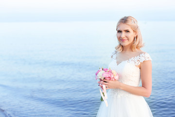 Fototapeta na wymiar Happy bride holding wedding bouquet on beach. Space for text