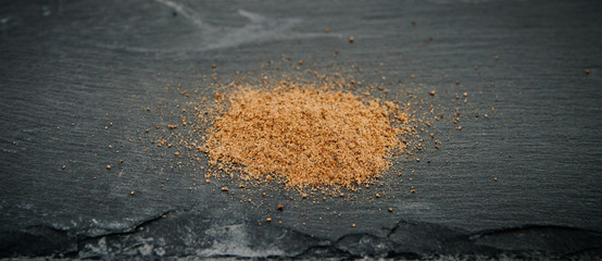 Ground nutmeg on a black, stone counter top. Nutmeg. The concept of seasoning dishes, using spices and herbs for meals.