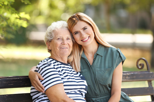 Woman with elderly mother on bench in park