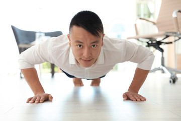 Young businessman doing exercises in office. Workplace fitness